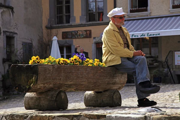Senior man sitting in the swiss village Gruyeres, Switzerland. — Stock Photo, Image
