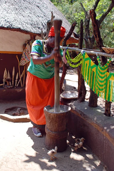 Mujer africana en vestido multicolor cocinando harina de maíz en Cultural Village Lesedi, Sudáfrica . — Foto de Stock