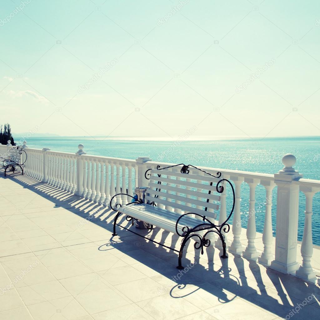 classic white balustrade, bench and empty terrace overlooking sea