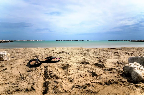 手前に海の見えるビーチとフリップフロップ — ストック写真