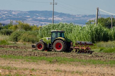 Traktör tarladaki toprağı sürüyor.