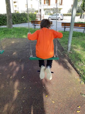 Salıncakta oynayan bir çocuğun arka görünüşü