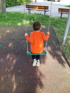 Salıncakta oynayan bir çocuğun arka görünüşü