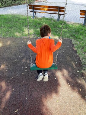 Salıncakta oynayan bir çocuğun arka görünüşü