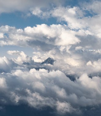 Dağın zirvesi bulutlarla çevrilidir. Dağlarda ağır bulutlar var. Beyaz bulutlarda güzel dağ manzarası.