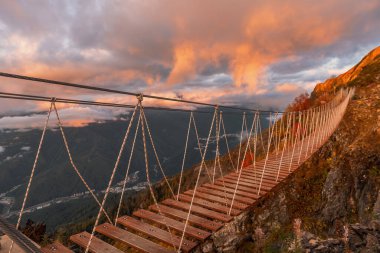 Dağlardaki asma köprü. Batan güneşin ışığında altın sonbahar.