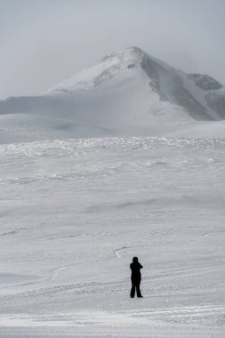 Arcasar Tepesi. Karachay-Çerkessia 'daki Arkhyz Dağları. Kar beyazı bir kış manzarası ve yalnız bir adam. İnsan ve dağ.