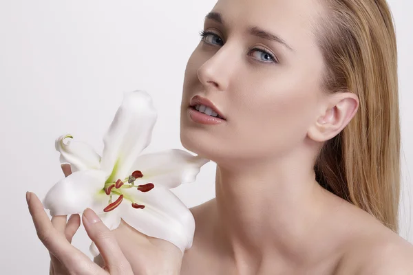 Skönhet blonda unga kvinnan visar en färsk blomma på vit — Stockfoto