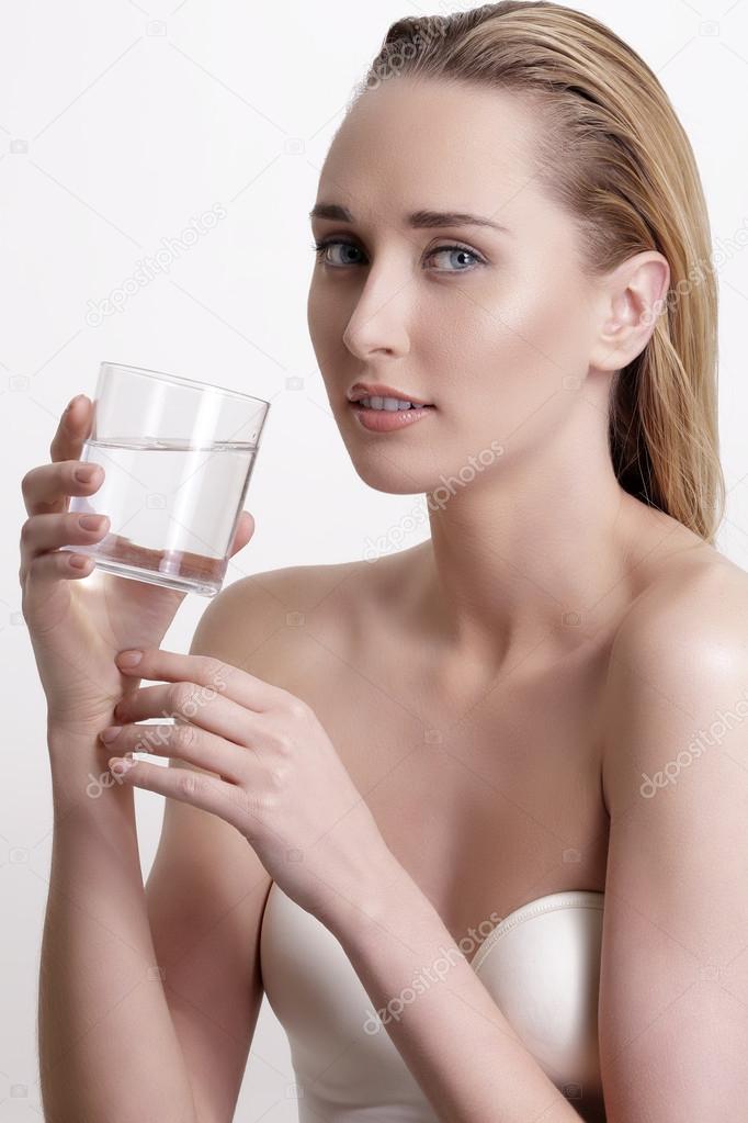young beautiful woman drinking fresh water on white