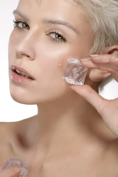 Hermoso modelo aplicando un tratamiento de belleza de hielo en la piel —  Fotos de Stock