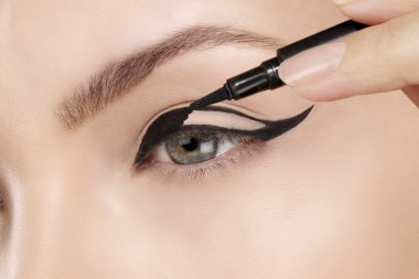 Beautiful model applying eyeliner closeup on eye clipart