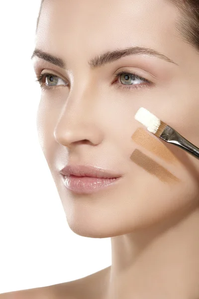 Beautiful model applying foundation with a brush — Stock Photo, Image