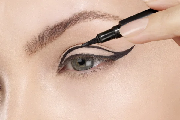 Hermoso modelo aplicando delineador de ojos primer plano en el ojo — Foto de Stock