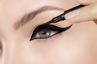 Beautiful model applying eyeliner closeup on eye clipart