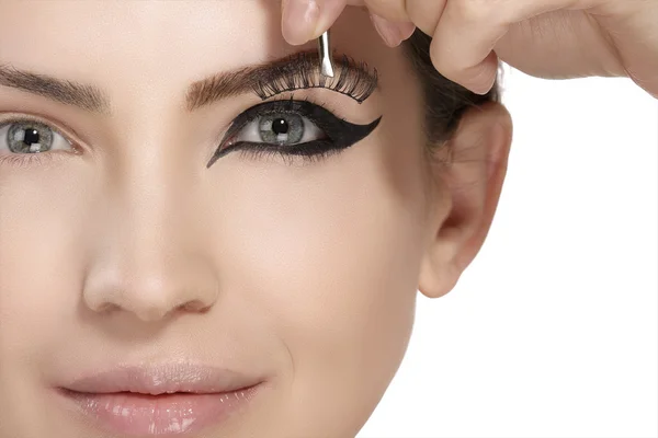 Model applying artificial eyelashes extension on smoky eye — Stock Photo, Image