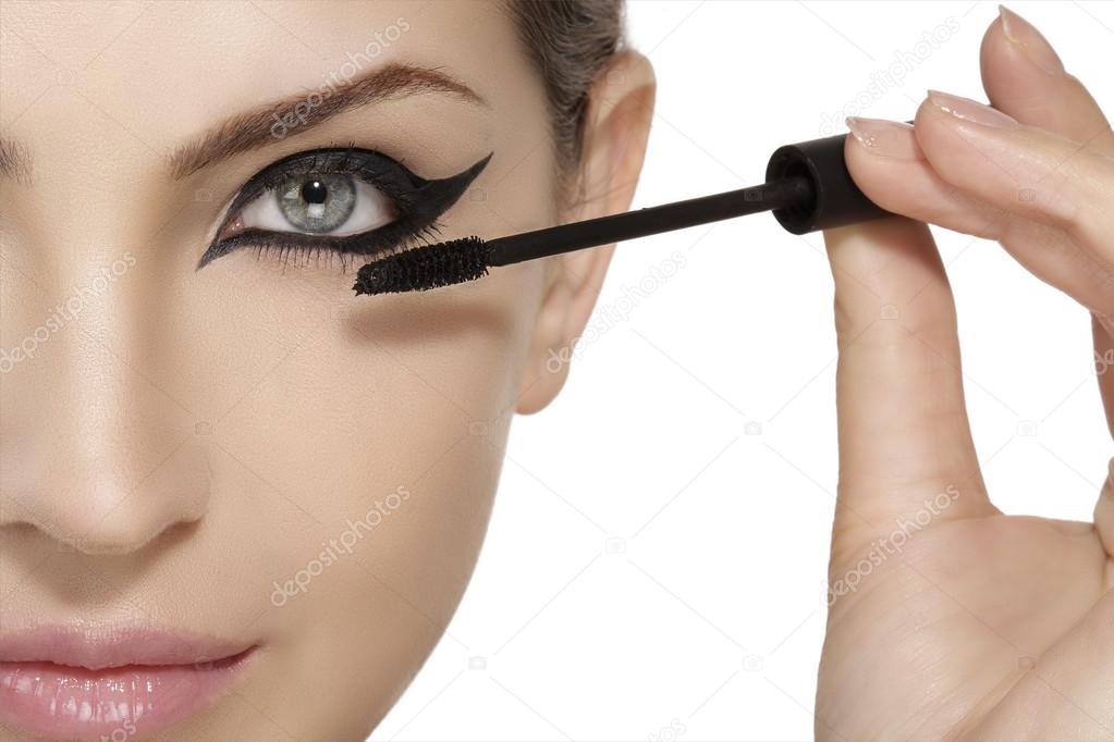 Beautiful model applying mascara on eyelashes  close up