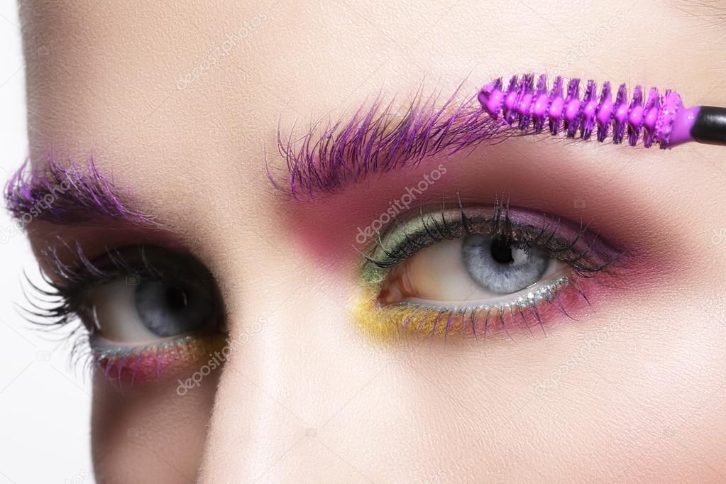Close up on eyes , making colorful eyeshadows and eyeliner