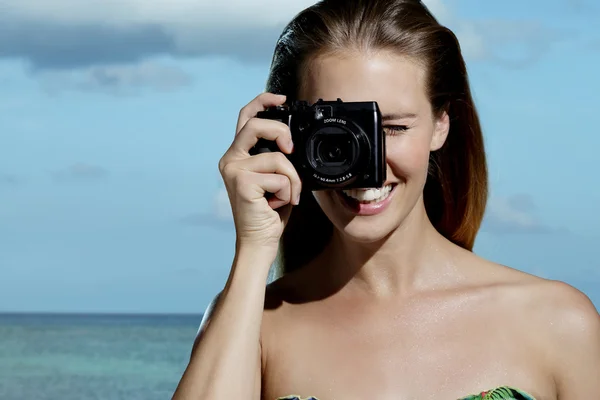 Beautiful smiling woman taking photos on the beach — Stock Photo, Image