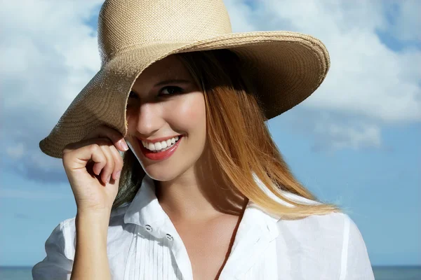 Естественная блондинка, улыбающаяся в шляпе на пляже — стоковое фото
