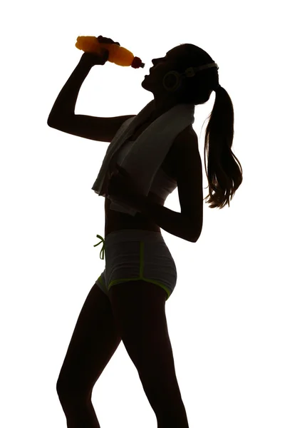 Una mujer ejercitando fitness bebiendo bebida energética en silueta —  Fotos de Stock