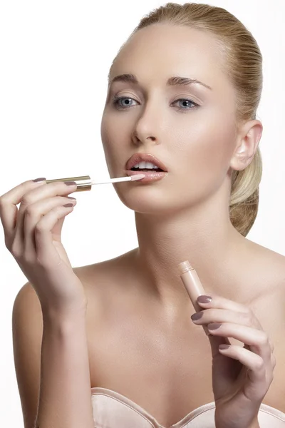 Hermosa mujer joven aplicando brillo labial — Foto de Stock