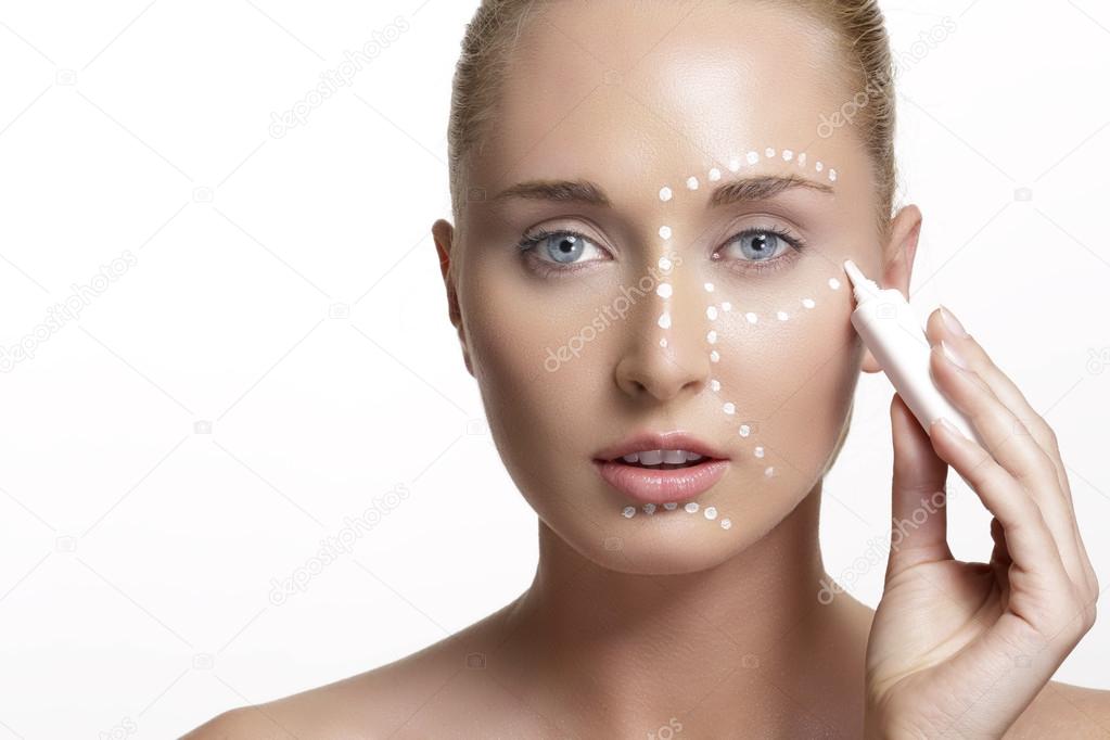 young beautiful woman applying creme on her skin