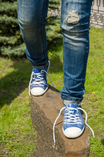 Legs in ripped jeans on the stone — Stock Photo, Image