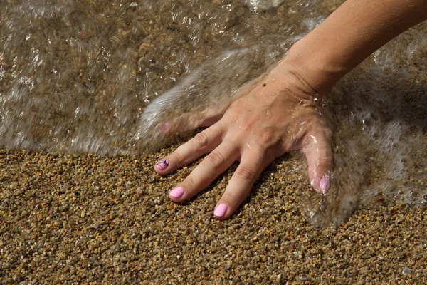 Wave covered hand on the beach — Stock Photo, Image