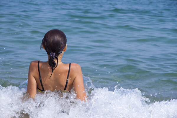 The girl from the back in a spray of sea water