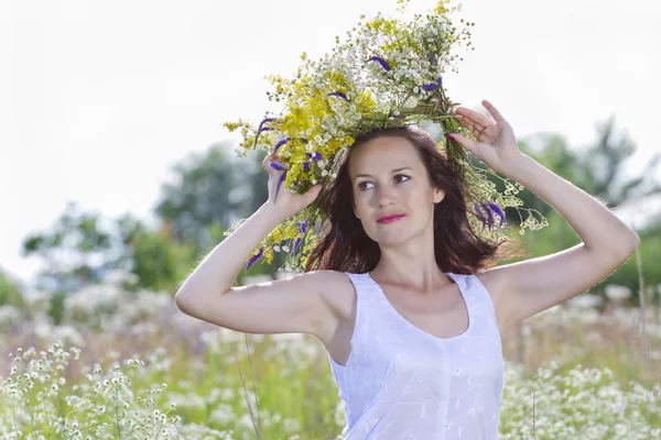 Meisje in een krans van veld-bloemen — Stockfoto