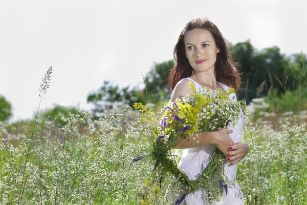 A menina no prado com uma coroa de flores de campo — Fotografia de Stock