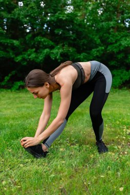 Genç kız doğada esneme hareketleri yapıyor.