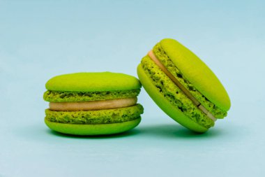 Mavi arka planda iki yeşil badem kurabiyesi.