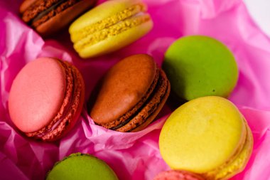 çok renkli badem kurabiyeleri pembe kağıt arka planda bir karton kutunun üzerinde