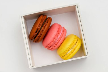 Beyaz arka planda beyaz bir kutuda üç renkli makarna keki.