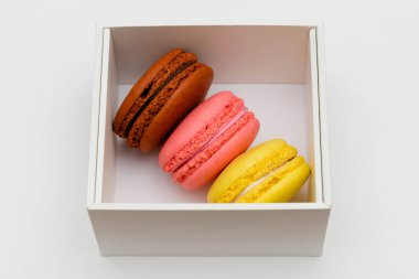 Beyaz arka planda beyaz bir kutuda üç renkli makarna keki.