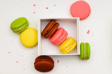 Beyaz arkaplanda beyaz bir kutuda çeşitli renkte makarna kekleri