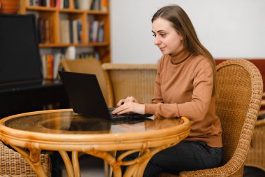 Genç kız bir laptopla kafede çalışıyor.