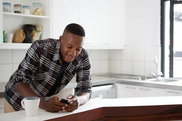 Man på köket med mobiltelefon — Stockfoto