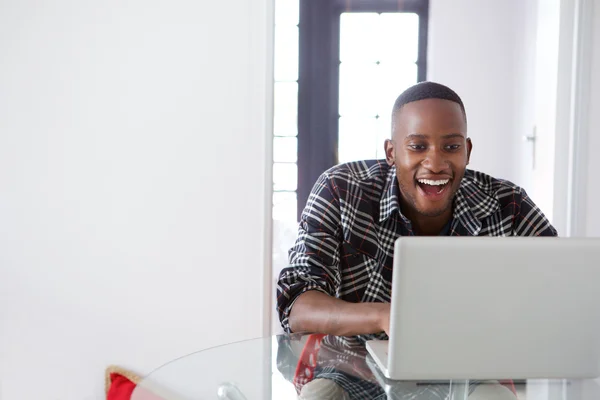 Lachende Afrikaanse man die op laptop werkt — Stockfoto