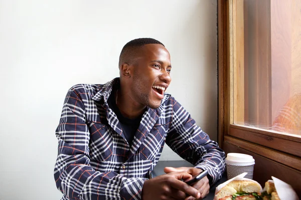 Sorrindo jovem africano sentado no café — Fotografia de Stock