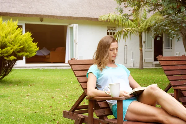 Mulher relaxante em casa jardim com livro — Fotografia de Stock