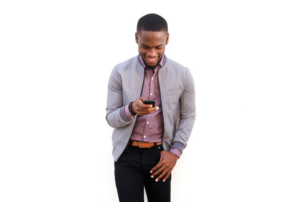 Portrait of a happy young black man sending text message on mobile phone against white background