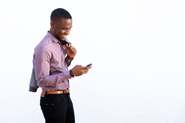 Portrait of a young african guy reading text message on cell phone against white background