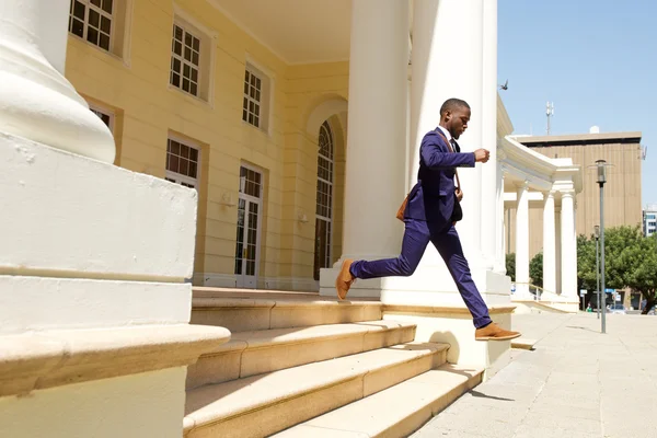 Молодой бизнесмен выбегает из здания — стоковое фото