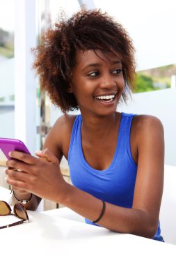 Cep telefonu kullanarak gülümseyen siyah kadın