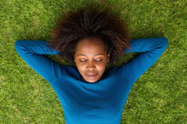 Young african woman lying on grass