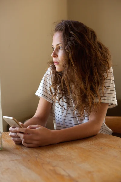 Treurige vrouw zitten met mobiele telefoon — Stockfoto