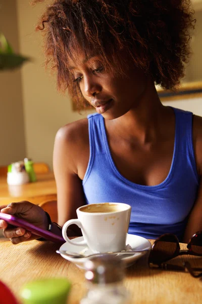 Jovem mulher sentada no café com telefone celular — Fotografia de Stock