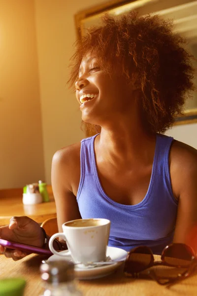 Mujer joven riendo con teléfono móvil en la cafetería — Foto de Stock